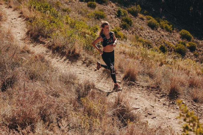 Fitness female running through mountain path