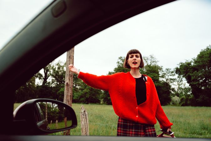 Woman in red sweater catching car on road
