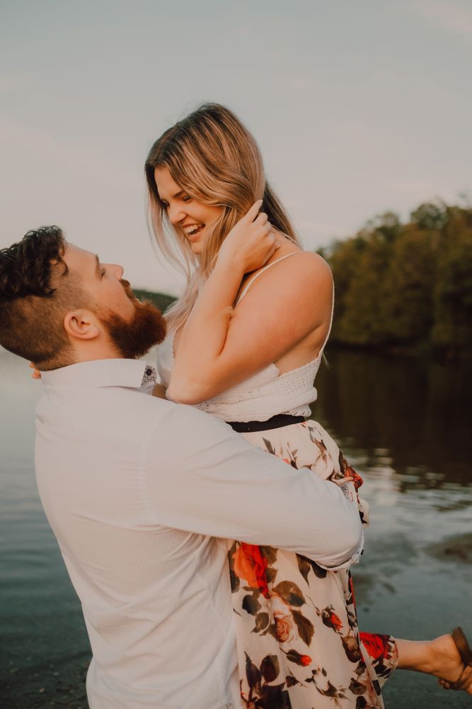 Loving man carrying happy woman on hands on shore