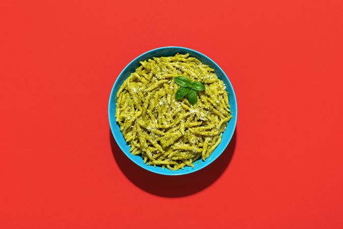 Pasta with pesto sauce, top view on a red background