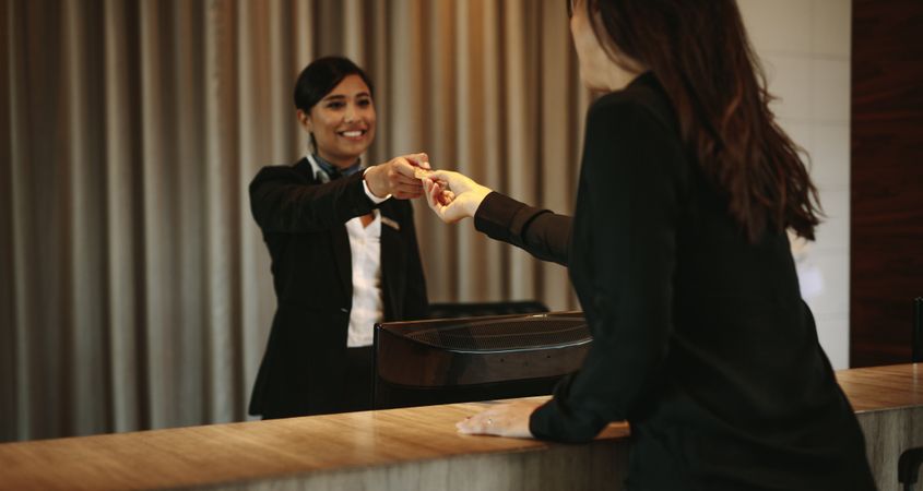 Female guest taking room key card at check-in desk
