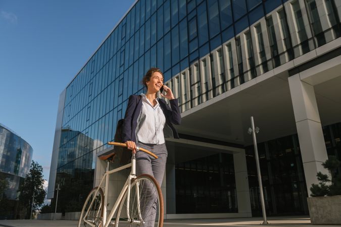 Cheerful manager with bicycle talking on smartphone