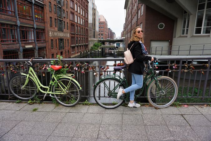 Young woman standing beside a bicycle parked on sidewalk in Hamburg, Germany