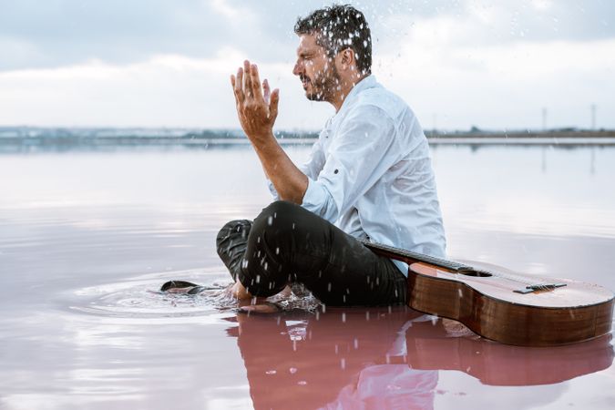 Musician with guitar on pink sandy water