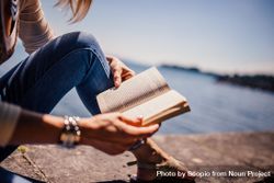 Close-up shot of woman reading a book near shoreline 5XJXKb