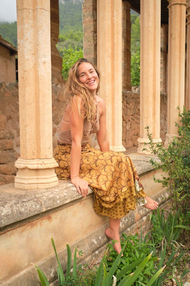 Happy woman sitting near old stone building