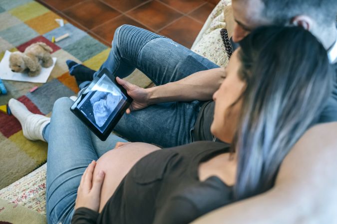 Pregnant with her partner looking ultrasound of their baby