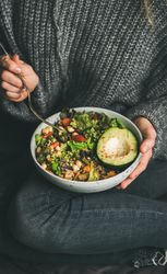 Woman in jeans and sweater holding bowl of fresh salad