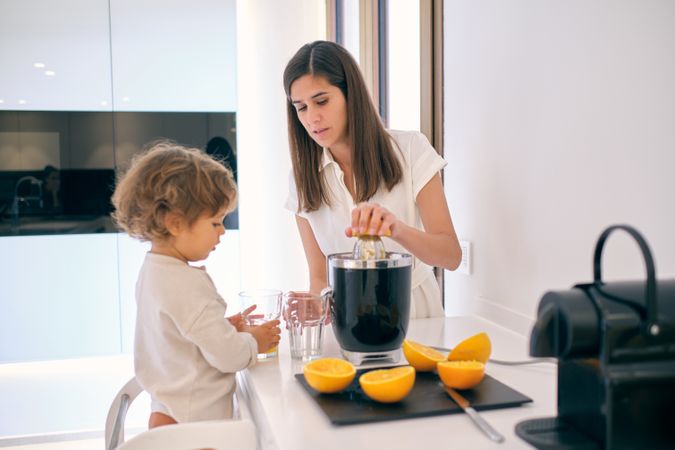Woman and toddler making fresh juice at home