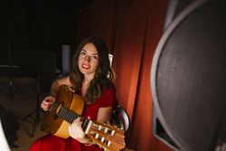 Creative woman singing and playing guitar on stage