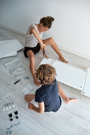 Serious mother and son assembling furniture at home