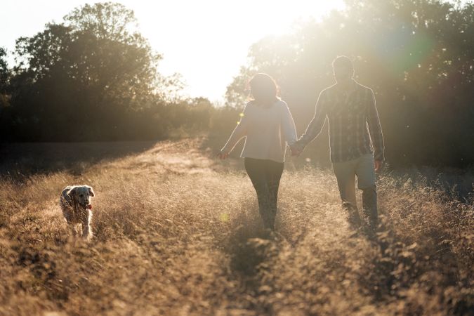 Couple with dog in countryside at sunset
