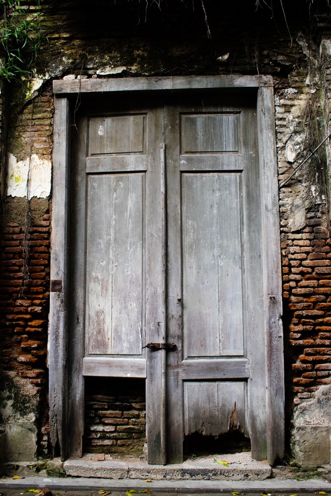 Big old broken wooden door on brick wall of historical building located in Kota Lama, Semarang City, Indonesia.