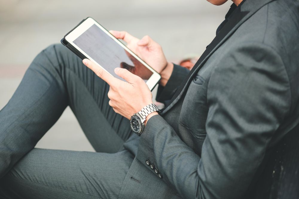 Man in suit sitting on floor and using tablet computer