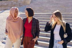 Female friends descending outside staircase and chatting on sunny day