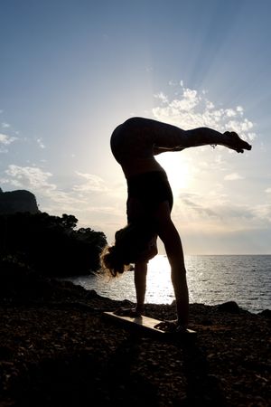 Silhouette of a woman practicing a variant of the handstand yoga
