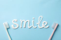 Word Smile made of toothpaste on blue background, top view
