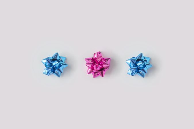 Row of plastic pink decorative gift bows bordering light background