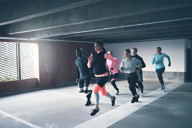 Group of people warming up by jogging in a parking lot