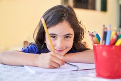 Creative cute schoolgirl taking notes on paper with pencil
