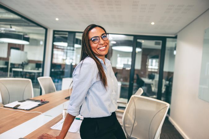Black businesswoman smiling cheerfully in modern boardroom