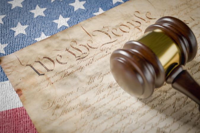 United States Constitution, Gavel and American Flag Resting on Table.