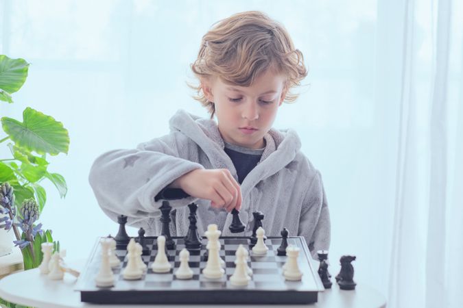 Focused preteen boy planning next move while playing chess