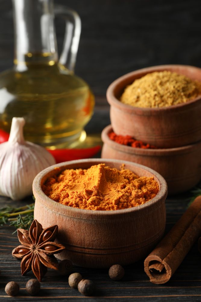 Wooden table scattered with spices and ingredients for cooking, vertical composition