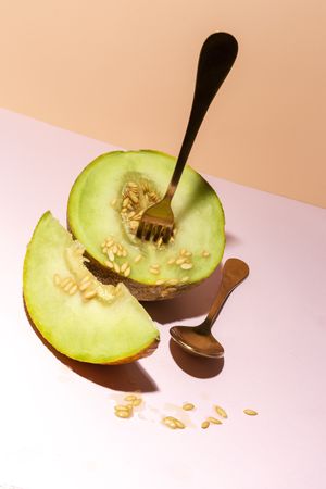 Sliced small melon on plate with spoon and fork