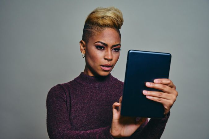 Black woman concentrating on typing on a tablet