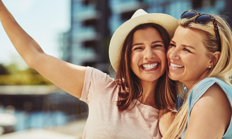 Women smiling with their faces together on sunny day