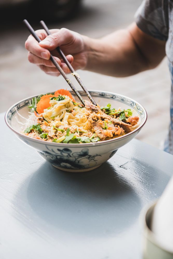 Man eating noodles at Vietnamese restaurant with chopsticks