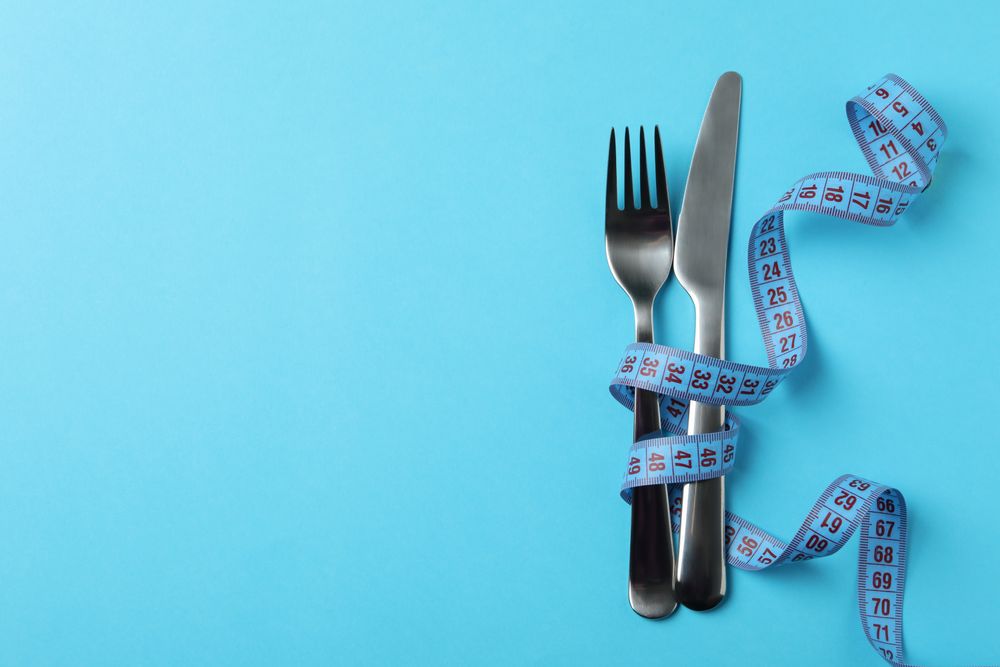 Cutlery with measuring tape on blue background