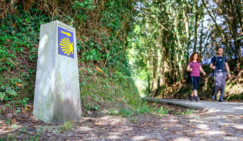 Signpost of Saint James way with pilgrims walking