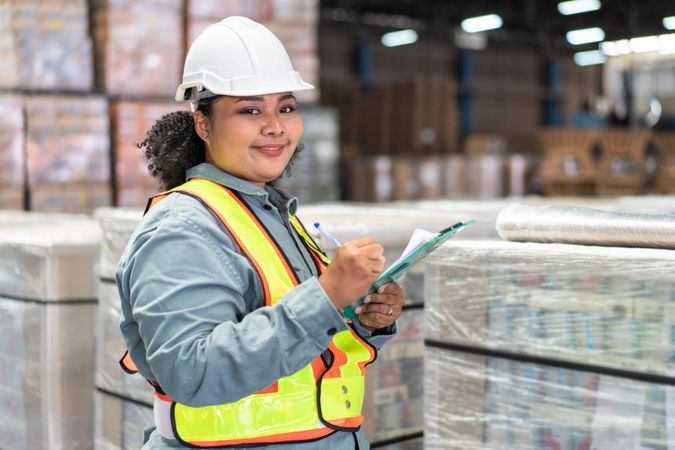 Woman in safety gear working in storehouse