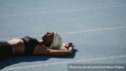 Woman athlete lying on the running track relaxing in the sun after workout 4daBDb