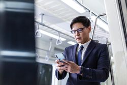 Businessman with smart phone standing in train car