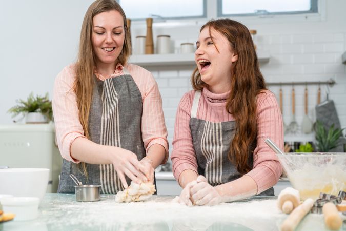 Mother and daughter laughing while baking together in the kitchen