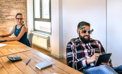 Businesswoman looking at her colleague who is wearing funny glasses because he is going on vacation