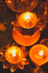 Lit diyas beside saffron flowers on a table