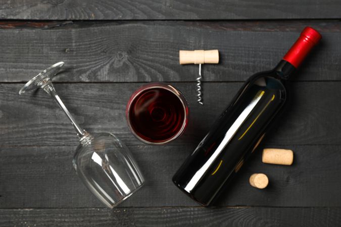 Flat lay composition with bottle of wine, glasses and corkscrew on wooden background, copy space