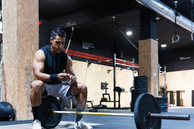Strong Hispanic sportsman near barbell