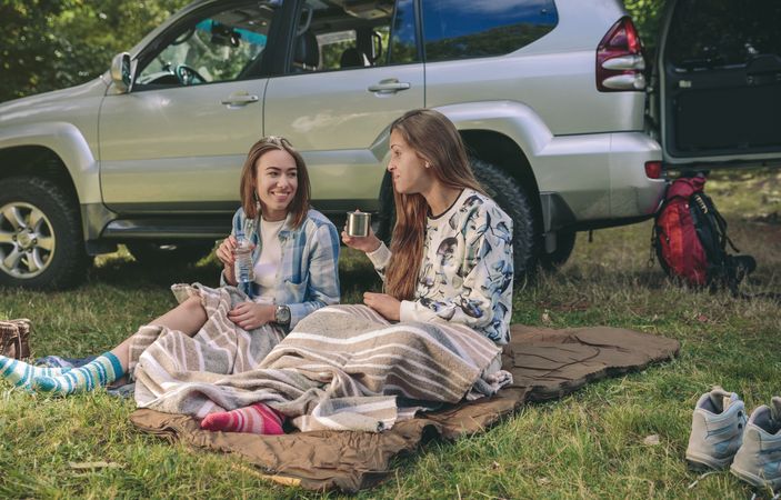 Women friends chatting and resting under blanket