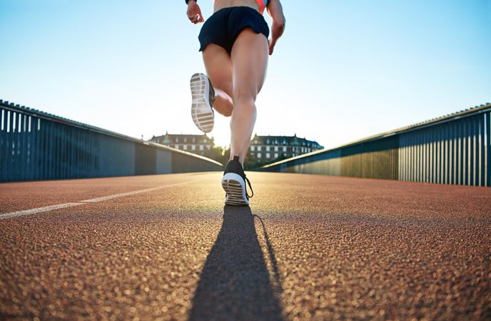 Shot of a female’s muscular legs running across a bridge