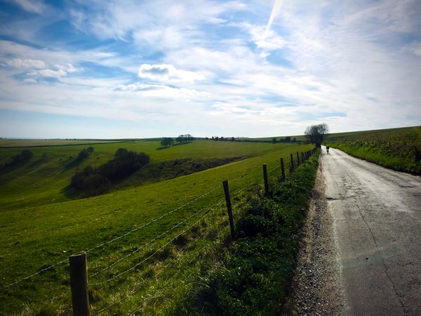 Lone cyclist riding uphill on rural road in English countryside
