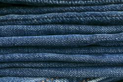 Stack of blue jeans as background, space for text