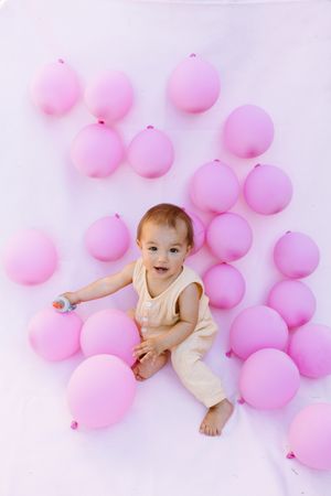 Cute baby sitting with colorful balloons