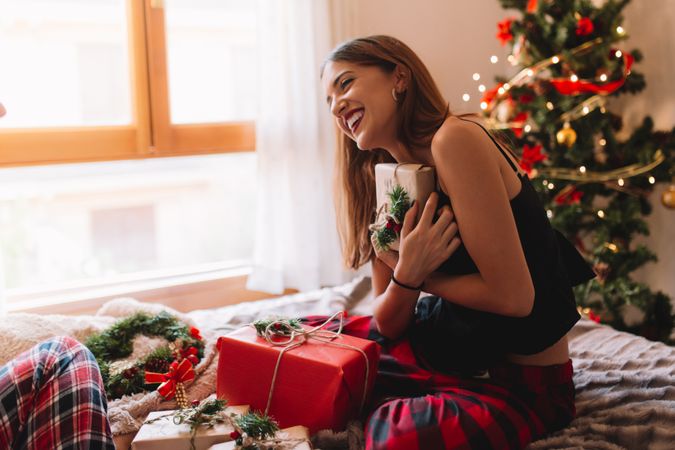 Portrait of beautiful and happy women opening gifts in cozy bed near christmas tree.