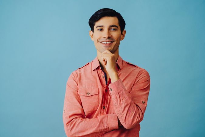 Mid portrait of curious Hispanic male smiling while looking at camera