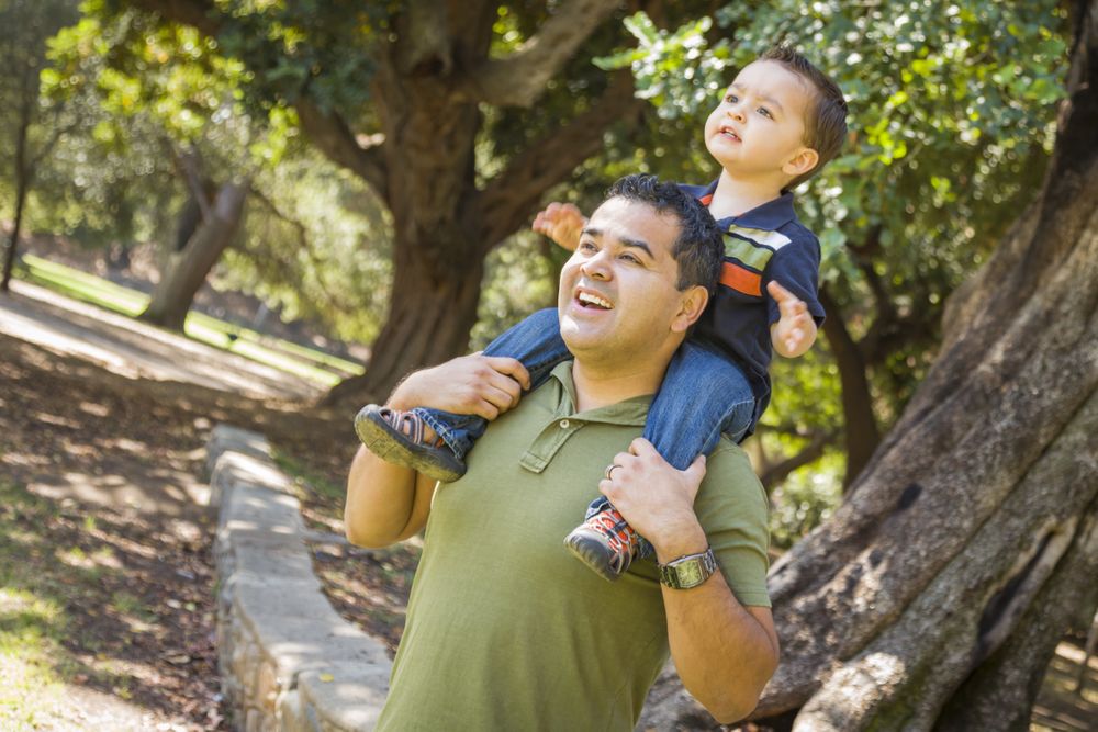 Son Enjoy a Piggy Back in the Park with Dad